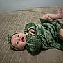 baby, blanket, child, cozy, cute, expression, fabric, face, feet, green_dress, hands, happy, headband, indoors, infant, lying_down, portrait, skin, smiling, toddler