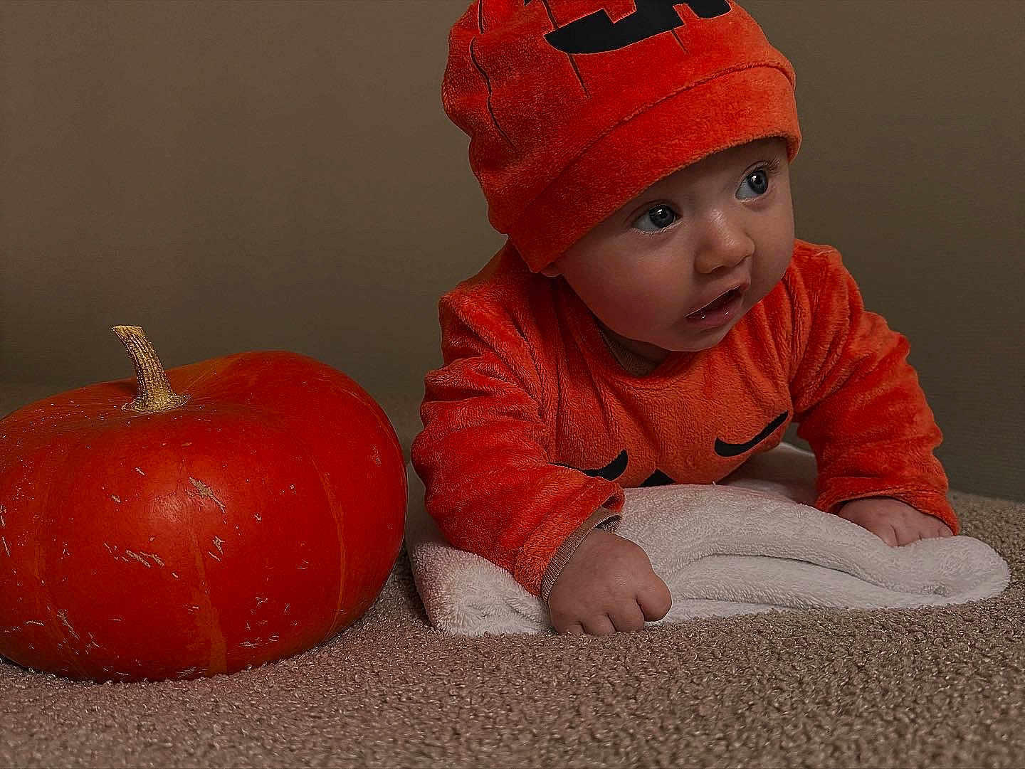 Zély a rejoint le concours — aidez-le/la à gagner de superbes lots ! baby, child, pumpkin, orange_clothing, hat, carpet, towel, indoor, cute, costume, face, hands, curious, holiday, autumn, seasonal, portrait, expression, crawling, soft_texture