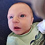 baby, infant, face, eyes, mouth, clothing, green_shirt, pattern, fish_design, texture, blue_background, closeup, portrait, child, newborn, skin, expression, looking_up, cute, young