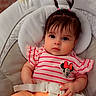 baby, child, infant, portrait, sitting, car_seat, cushion, seat_belt, pink_outfit, striped_clothing, minnie_mouse, bow, ponytails, dark_hair, brown_eyes, wide_eyed, indoors, close_up, front_facing, safe