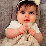 Mía Isabella Eireos joined the competition — help win amazing prizes! baby, infant, child, portrait, close_up, wide_eyes, headband, bow, dress, white_clothing, sitting, lying_down, indoors, blanket, couch, textile, hands, fashion, adorable, photography
