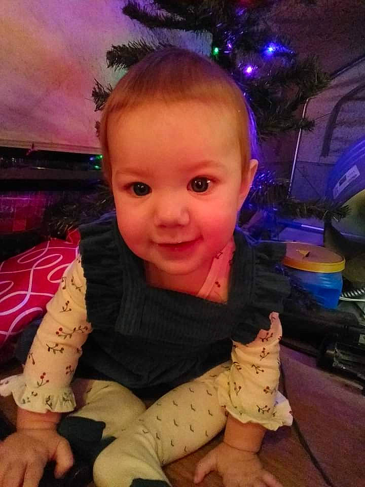 Jada is registered to the contest to win money with this photo: baby, baby_toddler_clothing, cheek, child, chin, christmas_tree, cool, electric_blue, event, flooring, foot, fun, happy, human_body, iris, joy, nose, organ, person, skin