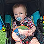 toddler, child, stroller, pacifier, blue_eyes, checkered_clothing, toy_mirror, reflection, sitting, outdoor, green_grass, colorful_toys, baby, infant, seatbelt, black_straps, plaid, cute, face, hand