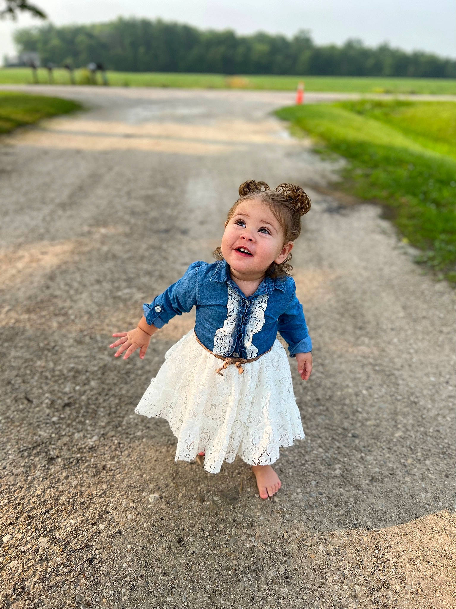 Oaklee is registered to the contest to win money with this photo: asphalt, body_of_water, child, dress, fun, gesture, grass, grass_family, grassland, happy, landscape, leisure, people_in_nature, person, plant, road, road_surface, sky, smile, toddler