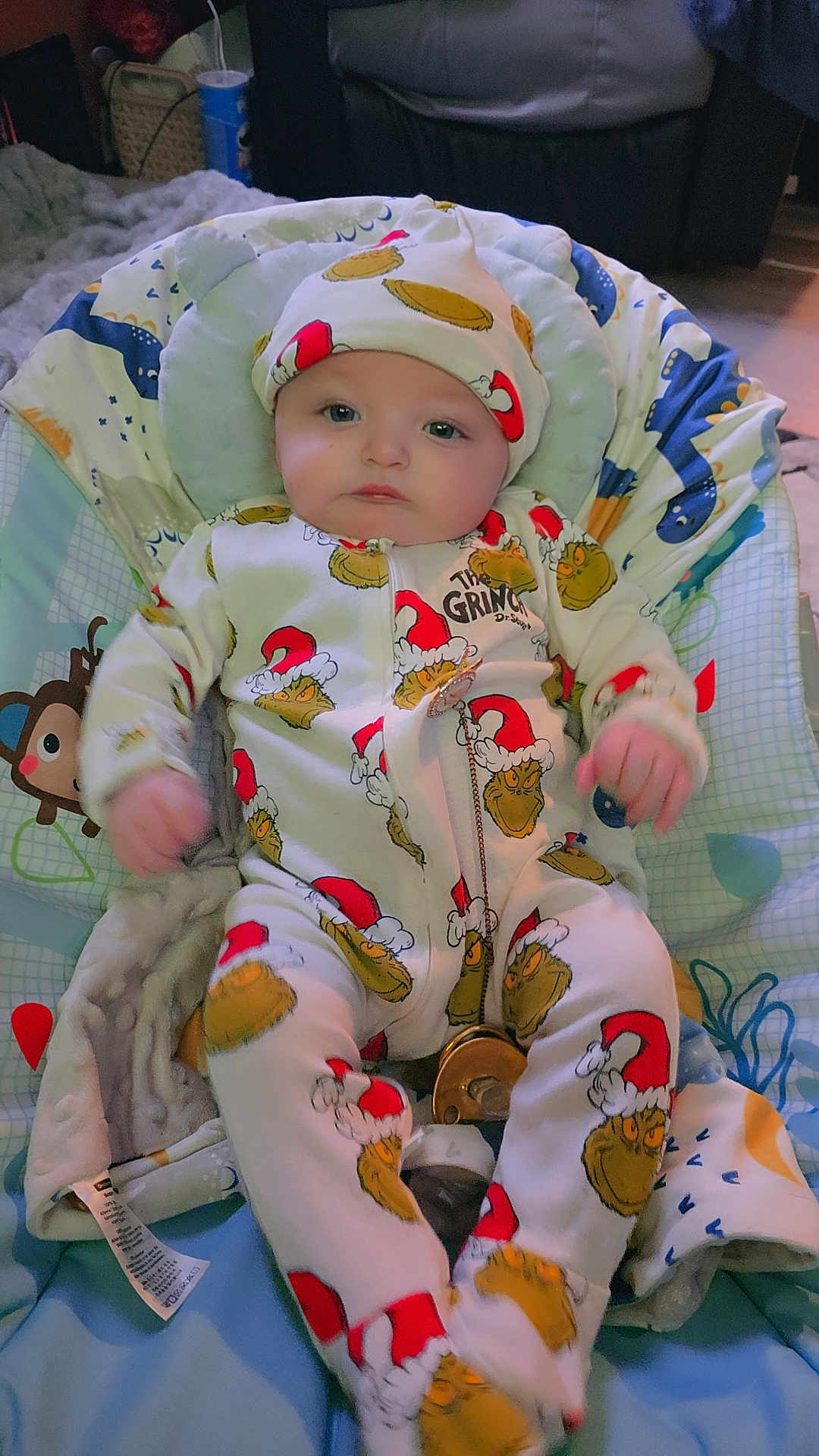 Marley joined the competition — help win amazing prizes! baby, infant, onesie, hat, grinch, baby_chair, blanket, indoor, person, clothing, cute, child, seated, soft_toys, fabric, smiling, face, headwear, holiday_theme, comfort