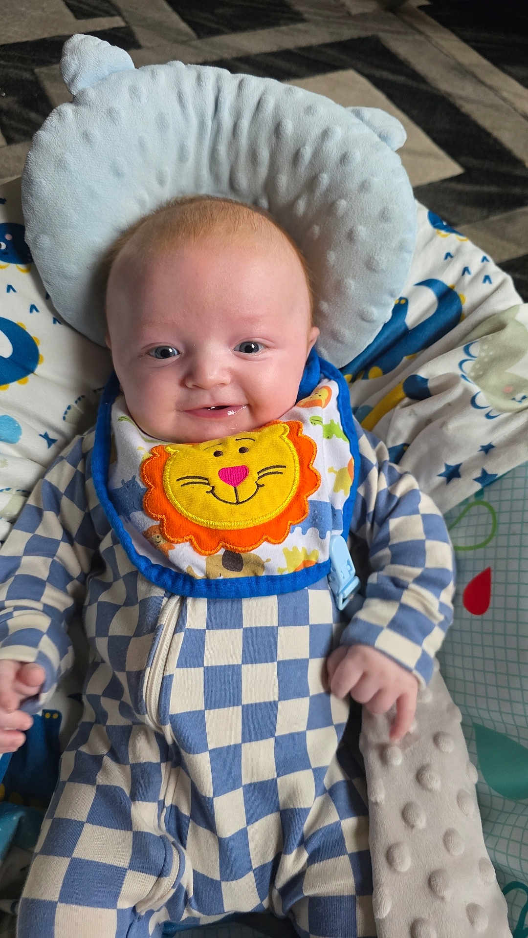 Marley joined the competition — help win amazing prizes! baby, smiling, infant, bib, checkered_clothing, blue, white, plush, cushion, face, head, happy, child, portrait, lying_down, soft_toys, baby_bedding, cute, teeth, hand