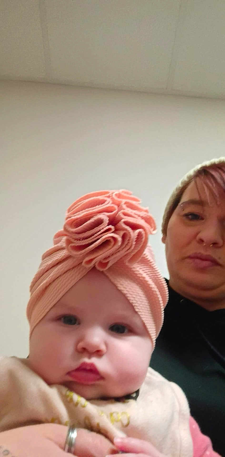 Emberly is registered to the contest to win money with this photo: baby, infant, child, adult, woman, selfie, portrait, headwear, turban, pink, beanie, face, cheeks, lips, eyes, hand, ring, indoor, ceiling, wall
