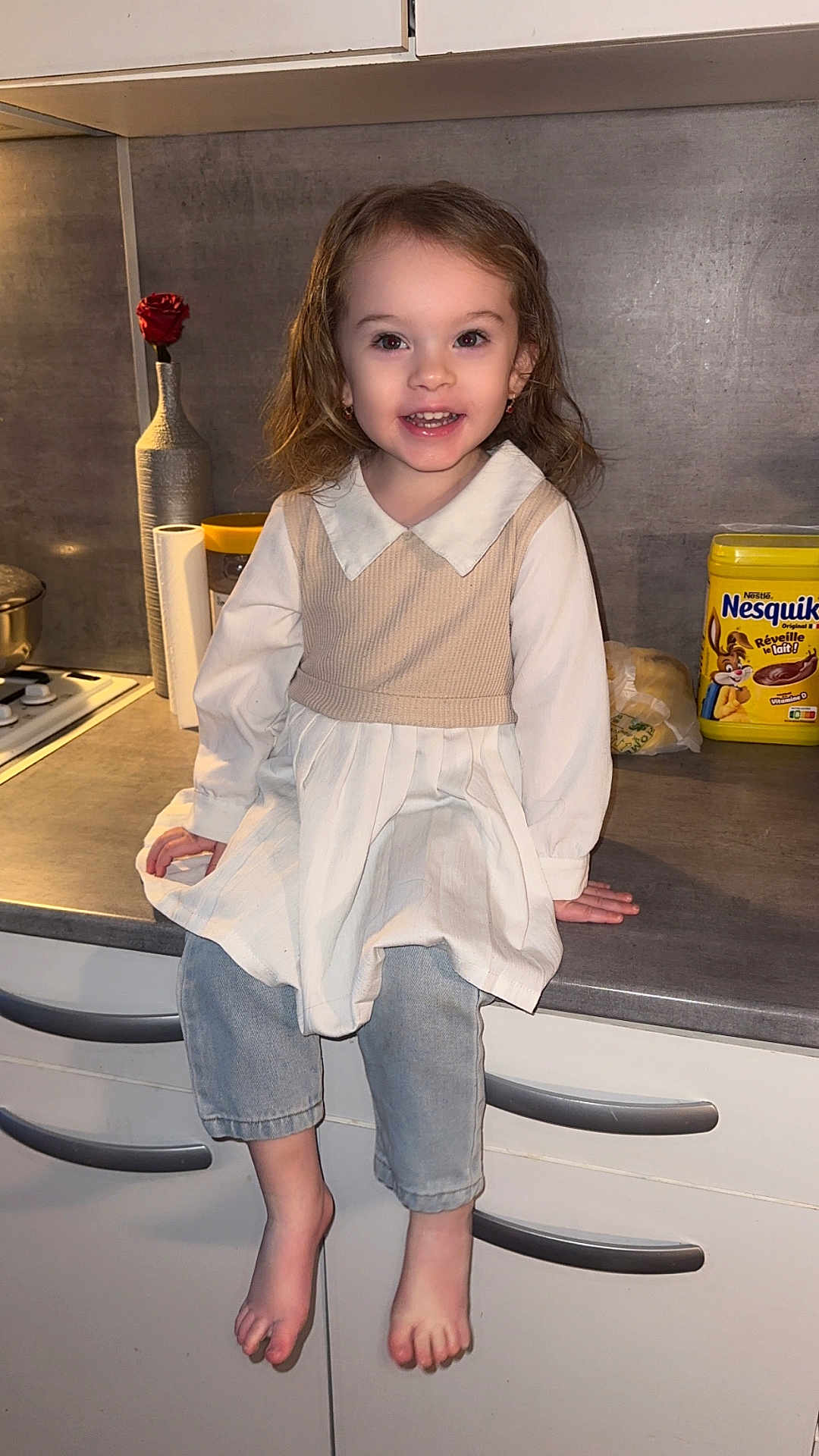 Ambre participe au concours pour gagner de l'argent avec cette photo : child, girl, smiling, barefoot, kitchen, counter, dress, vest, jeans, rose, vase, container, nesquik, food, cabinet, drawer, indoor, person, happy, portrait