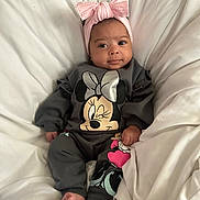 Evelynn is registered to the contest to win money with this photo: baby, infant, child, pink_bow, headband, minnie_mouse, clothing, onesie, smile, face, feet, blanket, bed, cute, indoors, portrait, person, happy, soft, resting