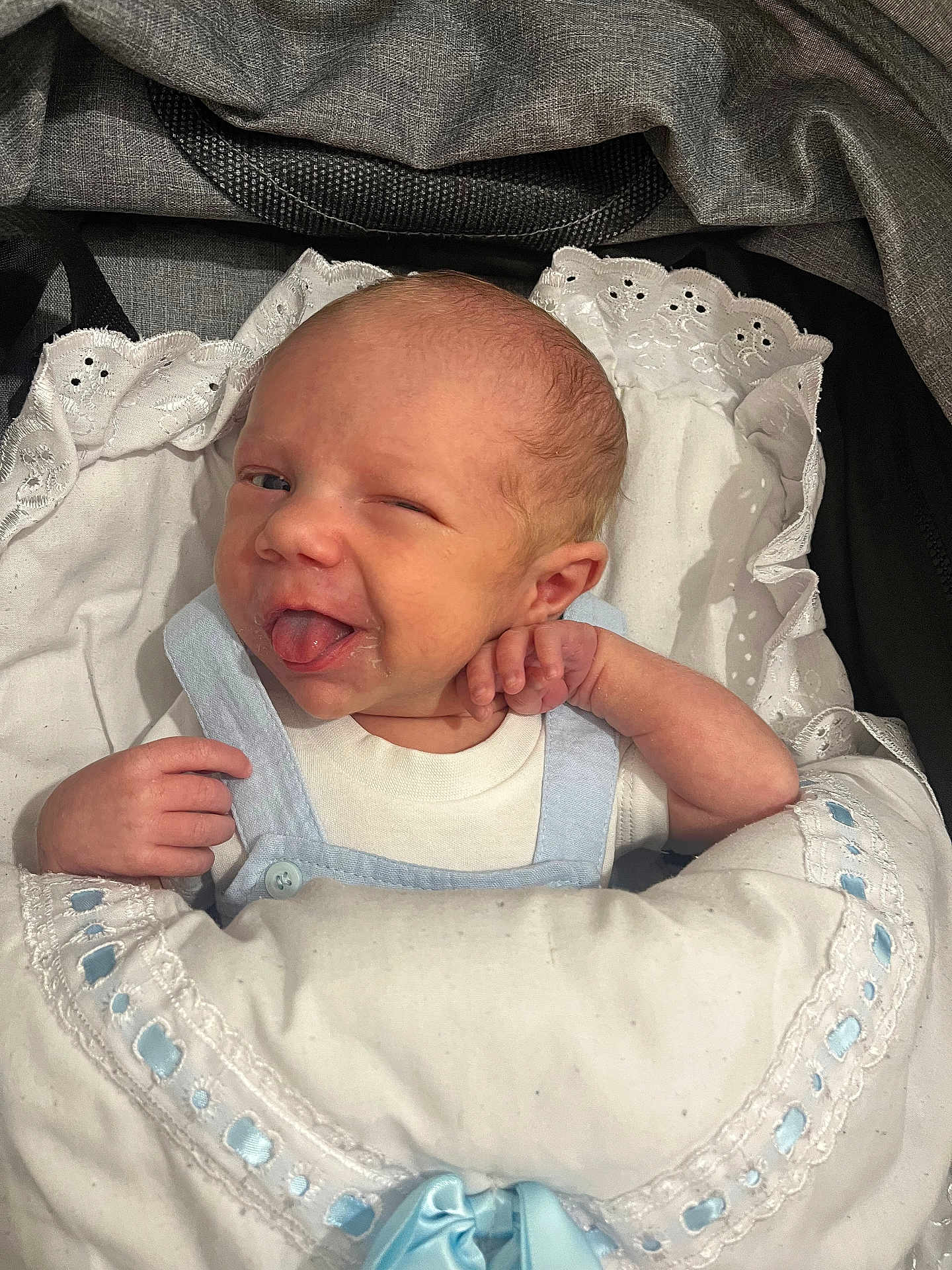 Lando is registered to the contest to win money with this photo: baby, newborn, blanket, blue_ribbon, winking, tongue_out, cute, infant, wrapped, white_clothing, smiling, face, hand, sleeping_bag, closeup, soft, indoors, portrait, child, cute_expression