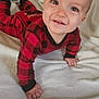 baby, child, infant, crawling, red_clothing, checkered_pattern, blanket, smiling, cute, indoors, soft_texture, happy, person, face, young, one_person, cozy, casual, head, hands