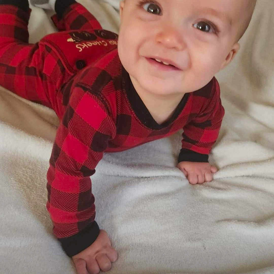 Leaym is registered to the contest to win money with this photo: baby, blanket, casual, checkered_pattern, child, cozy, crawling, cute, face, hands, happy, head, indoors, infant, one_person, person, red_clothing, smiling, soft_texture, young