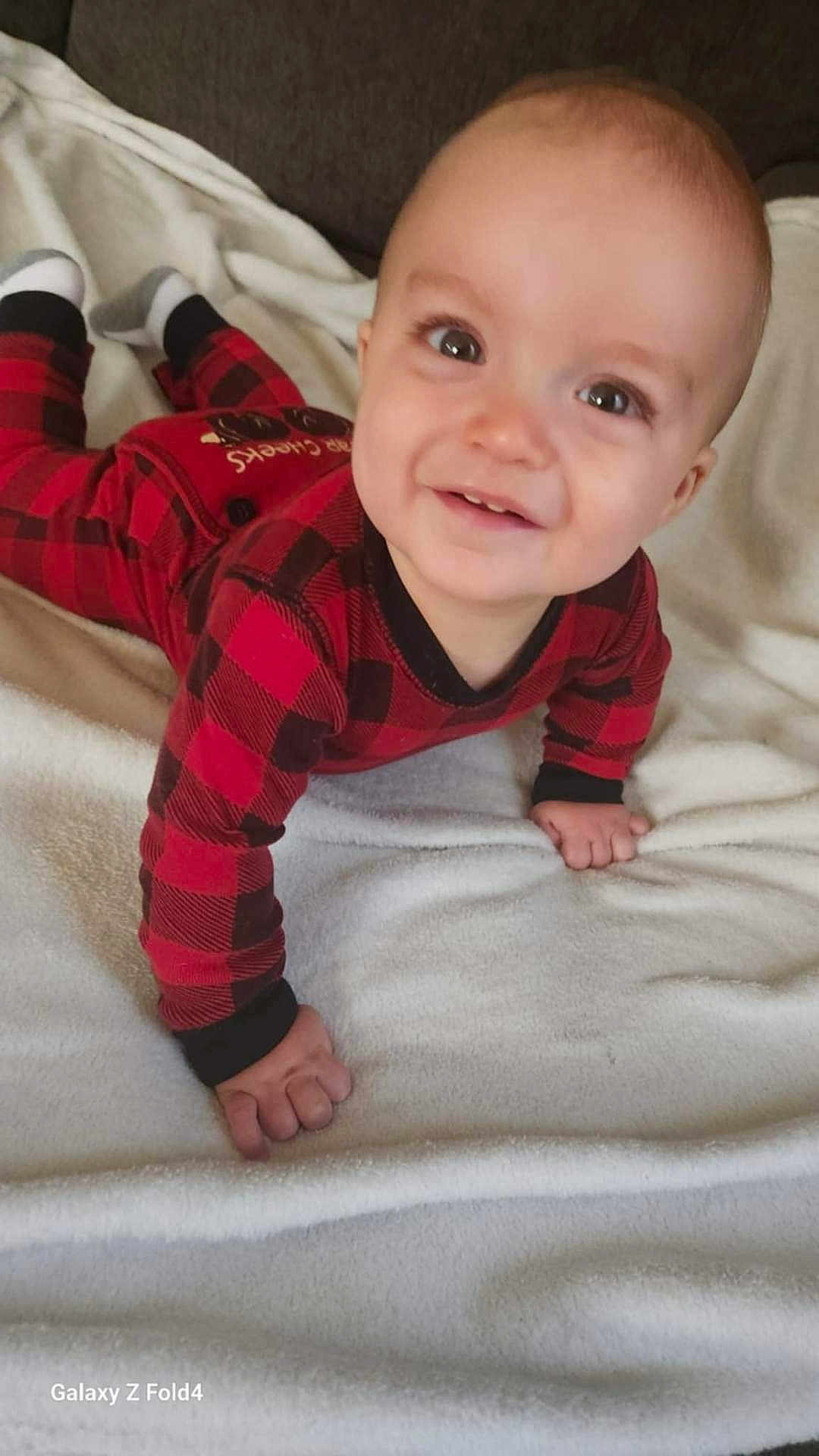 Leaym is registered to the contest to win money with this photo: baby, child, infant, crawling, red_clothing, checkered_pattern, blanket, smiling, cute, indoors, soft_texture, happy, person, face, young, one_person, cozy, casual, head, hands