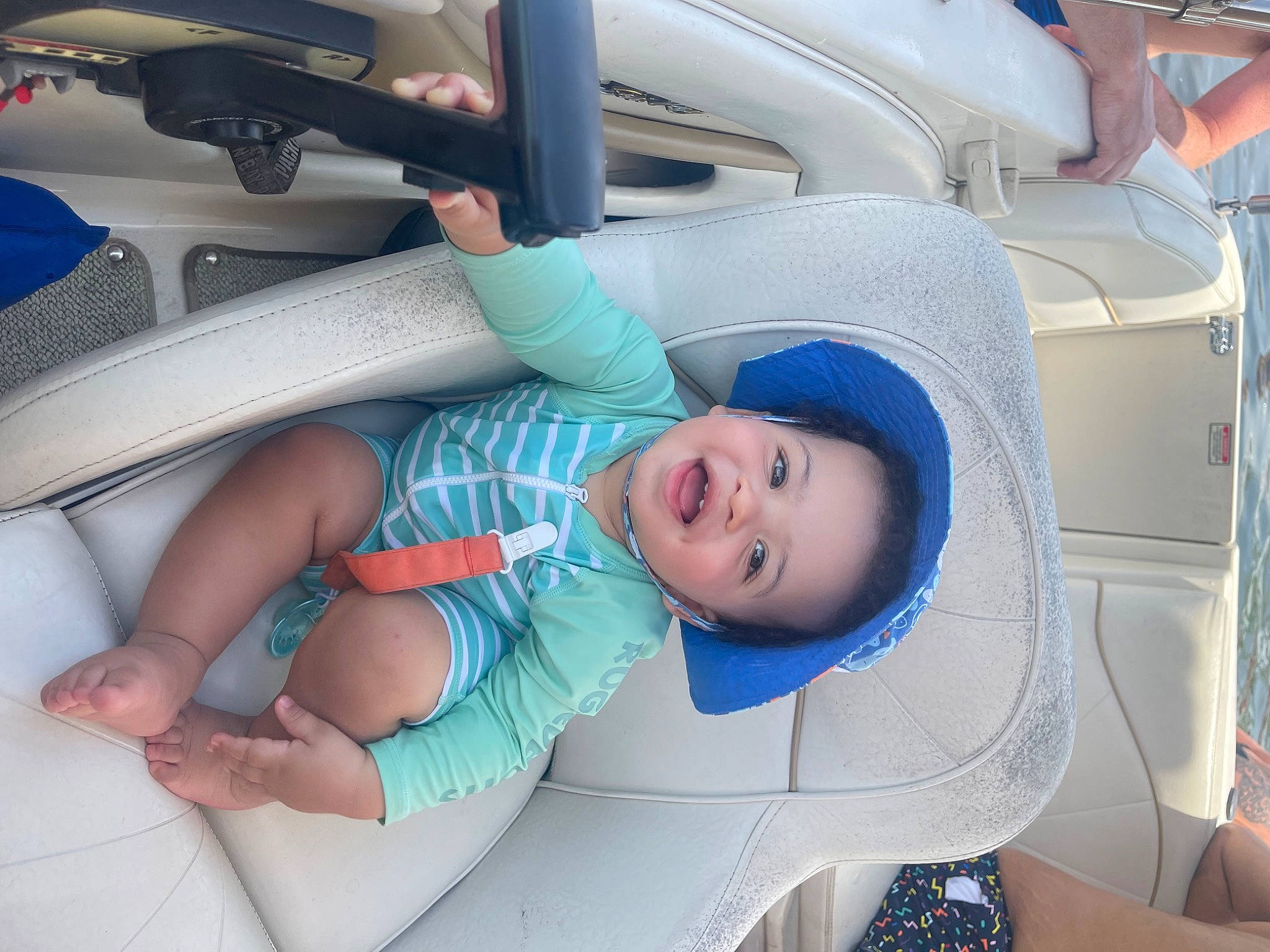 Desmond is registered to the contest to win money with this photo: auto_part, automotive_design, automotive_exterior, baby, baby_products, baby_toddler_clothing, car_seat, child, comfort, electric_blue, hat, health_care, motor_vehicle, person, product, service, skin, smile, thumb, toddler