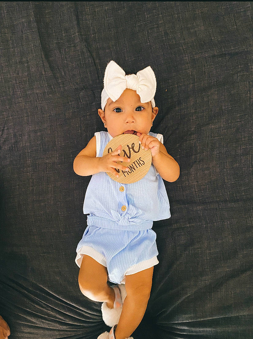 Janaya joined the competition — help win amazing prizes! abdomen, baby, baby_toddler_clothing, chest, elbow, flash_photography, gesture, happy, head, headwear, human_body, human_leg, knee, person, shorts, sleeve, stomach, t_shirt, thigh, toddler