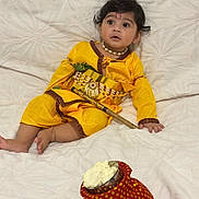 Devansh joined the competition — help win amazing prizes! child, baby, yellow_clothing, traditional_dress, necklace, bracelet, decorative_stick, red_pouch, white_blanket, indoor, portrait, cute, sitting, face, curious, soft_texture, cultural, festive, young_child, footwearless