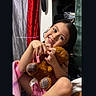 child, smiling, teddy_bear, toy, blanket, clothing, indoors, portrait, happy, cute, person, face, hair, sitting, furniture, colorful, cozy, young, holding, expression