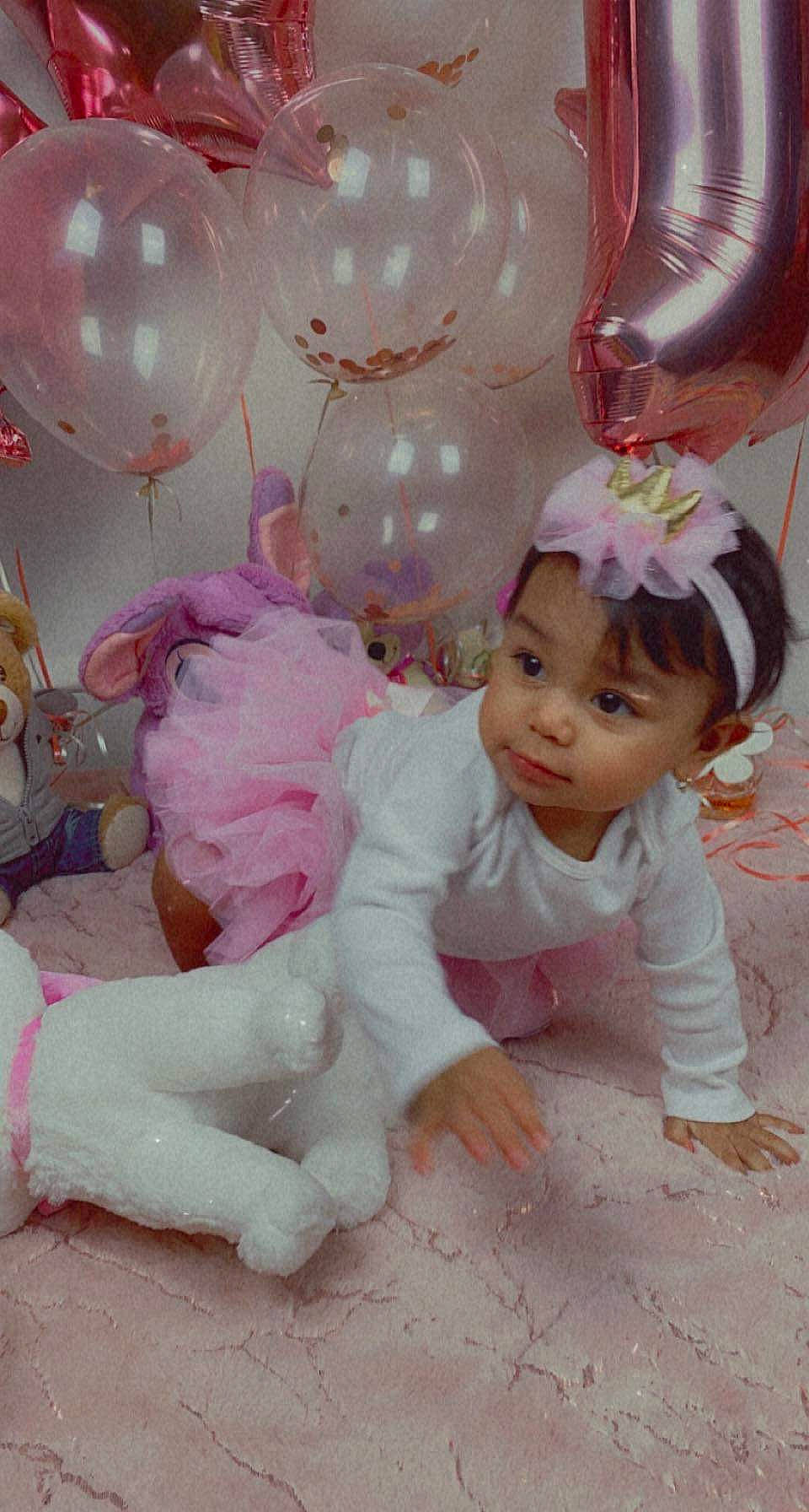 Catalina is registered to the contest to win money with this photo: baby, baby_toddler_clothing, balloon, child, event, fun, hair_accessory, happy, headpiece, magenta, mythical_creature, party_supply, peach, person, pink, room, sitting, smile, toddler, toy