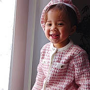 Onyx joined the competition — help win amazing prizes! child, toddler, smiling, pajamas, hat, window, indoor, natural_light, happy, cozy, portrait, face, person, clothing, cute, young_child, sitting, home, warm_colors, fabric