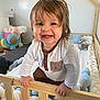 toddler, child, crib, wooden_rail, smile, happy, indoor, plush_toy, cushion, bed, clothing, person, face, hair, hand, baby, room, furniture, playful, cute
