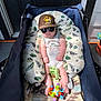 Bowen is registered to the contest to win money with this photo: baby, stroller, sunglasses, cap, toy, blanket, cushion, infant, outdoor, sunlight, clothing, person, footwear, headwear, seat, pattern, relaxing, summer, cute, child
