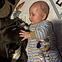 animal, baby, blanket, bond, child, comfort, cute, dog, face, friendship, indoor, infant, lying_down, mammal, pet, playful, striped_clothing, together, touching, young_child