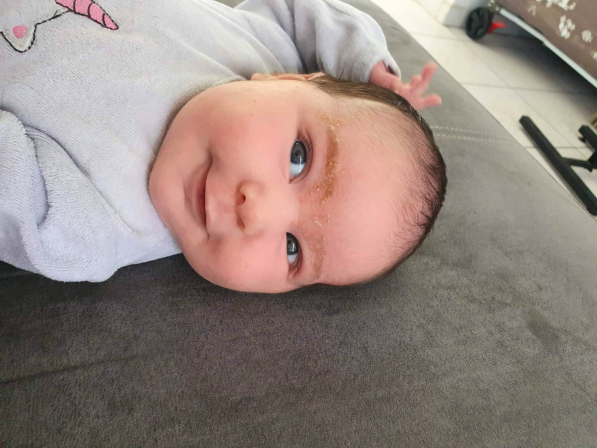 Luna participe au concours pour gagner de l'argent avec cette photo : baby, baby_toddler_clothing, cheek, child, comfort, eyelash, flooring, fur, headwear, iris, linens, lip, nose, pattern, person, portrait_photography, remote_control, room, skin, sleeve