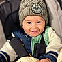 baby, blanket, bundle, child, clothing, cozy, cute, face, hand, happy, hat, indoors, infant, jacket, knit_hat, pom_pom, portrait, smiling, stroller, warm