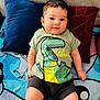 baby, child, infant, tshirt, dinosaur, cushion, blanket, sofa, indoor, cute, smiling, person, clothing, portrait, sitting, shorts, sock, face, head, playful