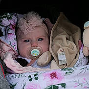 Esmée a rejoint le concours — aidez-le/la à gagner de superbes lots ! adorable, baby, baby_carrier, blanket, blue_eyes, child, clothing, cozy, cute, fabric, floral_pattern, flower, headband, indoor, infant, pacifier, pink, portrait, soft_toys, tulle
