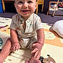 baby, child, smiling, onesie, play_mat, floor, indoor, crib, mirror, reflection, hand, foot, happy, cute, infant, person, room, wooden_furniture, car_pattern, palm_tree_pattern