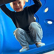 Carter is registered to the contest to win money with this photo: child, toddler, smiling, playground, blue, jeans, socks, crouching, happy, outdoor, play, fun, person, casual_clothing, head, face, light, young_child, cute, activity
