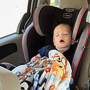 Carter is registered to the contest to win money with this photo: toddler, child, car_seat, blanket, sleeping, car_interior, seatbelt, window, sunlight, nap, child_safety, clothing, red_blanket, car, seat, headrest, interior, comfort, young_child, relaxation