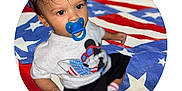 Brashaun joined the competition — help win amazing prizes! toddler, child, pacifier, curly_hair, mickey_mouse, shirt, socks, blanket, american_flag, red, white, blue, indoor, portrait, cute, baby, clothing, pattern, person, sitting
