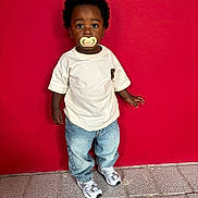 Kaïs a rejoint le concours — aidez-le/la à gagner de superbes lots ! toddler, child, pacifier, red_wall, jeans, tshirt, sneakers, standing, curious, outdoor, sidewalk, portrait, casual_clothing, young_child, looking_at_camera, urban, cute, full_body, fashion, street