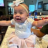 Naomi joined the competition — help win amazing prizes! baby, child, tutu, headband, smile, kitchen, counter, table, shirt, sitting, person, legs, arms, indoor, home, window, furniture, happy, easter, cute