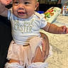 Naomi is registered to the contest to win money with this photo: baby, child, smiling, easter, headband, bow, tutu, socks, white_clothing, happy, indoor, table, snacks, person, holding, celebration, festive, cute, toddler, family