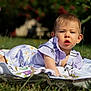baby, blanket, candid, child, daisy_pattern, daytime, expression, face, grass, head, infant, nature, outdoor, person, portrait, purple_clothing, skin, summer, sunlight, young_child