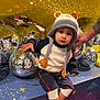 toddler, child, hat, animal_hat, disco_balls, reflection, yellow_background, red_carpet, striped_socks, sitting, hand, indoor, playful, curious, cute, knitwear, casual_clothing, toy, decor, person