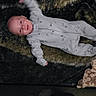 John is registered to the contest to win money with this photo: baby, child, onesie, blanket, playpen, mesh, smiling, waving, infant, lying_down, soft_texture, cozy, happy, indoor, patterned, clothing, person, portrait, cute, young
