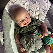 Luca is registered to the contest to win money with this photo: baby, infant, smiling, bouncer, toy, plush_toy, striped_shirt, onesie, face, hands, legs, seat, blanket, patterned_fabric, cozy, indoor, portrait, closeup, happy, lovey