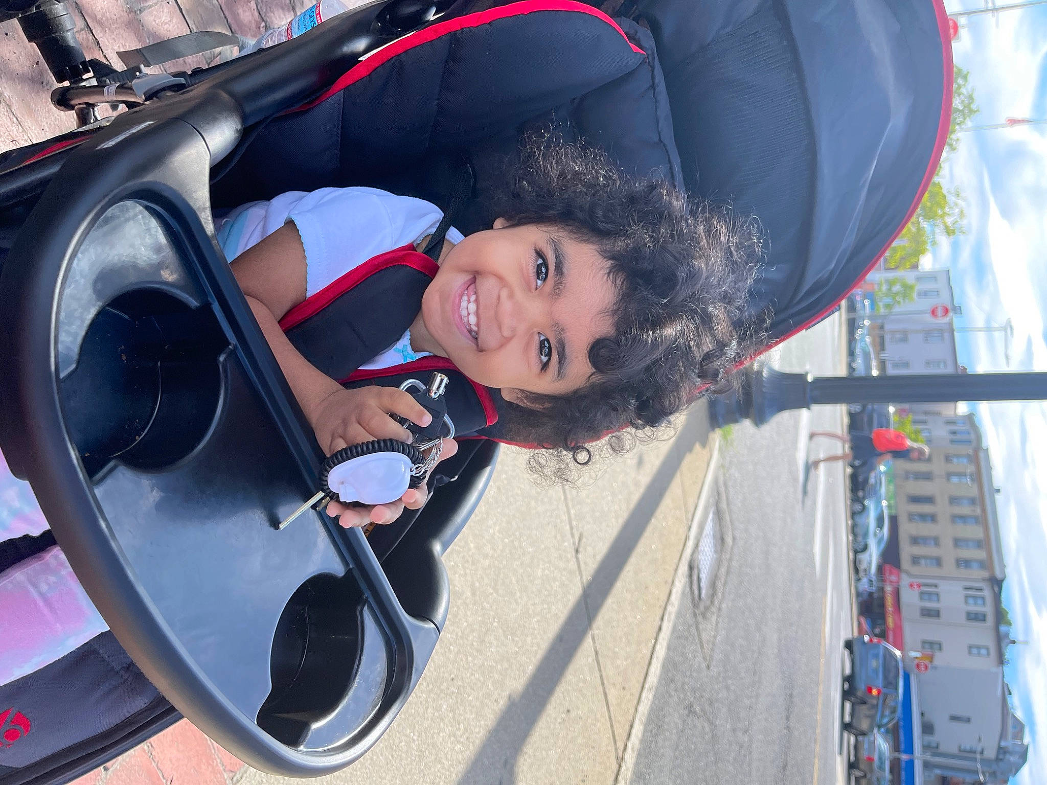 Carlee is registered to the contest to win money with this photo: auto_part, automotive_design, automotive_exterior, automotive_lighting, automotive_tire, automotive_wheel_system, blue, bumper, car, electric_blue, fun, hat, joy, motor_vehicle, person, public_space, rim, smile, toddler, vehicle