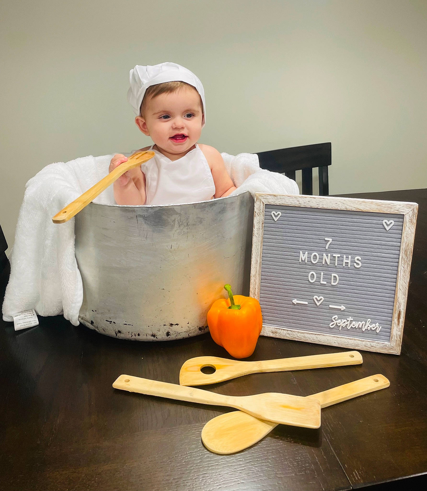 Becky is registered to the contest to win money with this photo: baby, baby_toddler_clothing, chef, child, cooking, dress, flooring, fruit, hand, happy, natural_foods, orange, peach, person, pumpkin, room, sitting, sleeve, tableware, toddler