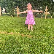Danica joined the competition — help win amazing prizes! arms_outstretched, casual, child, daylight, fence, girl, grass, greenery, happy, nature, outdoor, person, pink_dress, playful, smile, standing, summer, sunlight, tree, yard