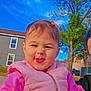 toddler, child, pink_clothing, puffy_vest, smile, face, outdoor, tree, blue_sky, house, window, fence, grass, person, daylight, playful, cute, hair_bow, expression, portrait