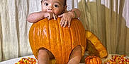 Juan is registered to the contest to win money with this photo: baby, pumpkin, candy_corn, table, blanket, curtain, child, cute, orange, fall, autumn, holiday, decor, foot, hand, bracelet, face, indoor, food, seasonal