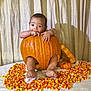Juan is registered to the contest to win money with this photo: baby, pumpkin, candy_corn, table, blanket, curtain, child, cute, orange, fall, autumn, holiday, decor, foot, hand, bracelet, face, indoor, food, seasonal