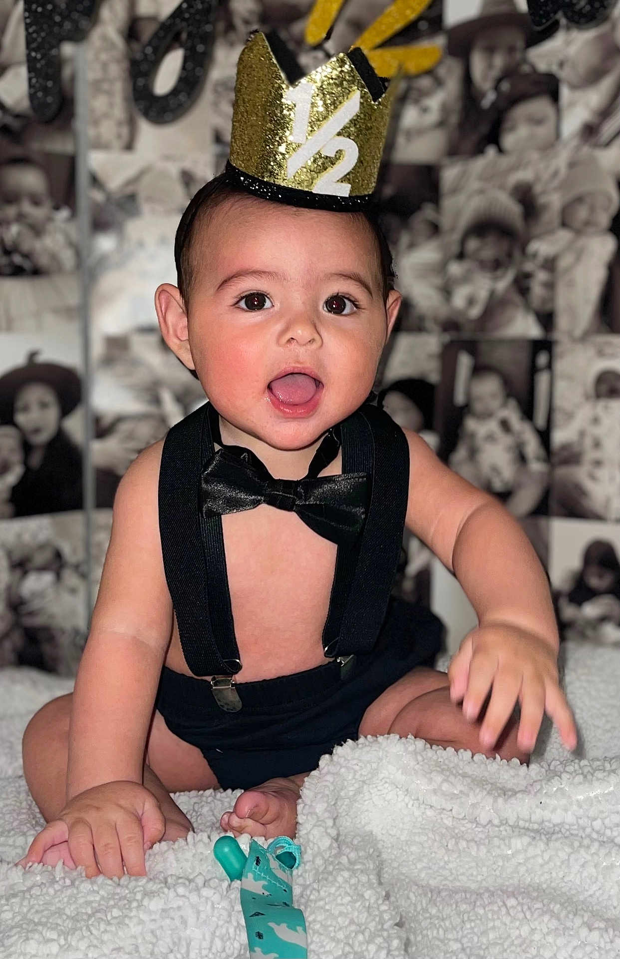 Juan is registered to the contest to win money with this photo: baby, child, crown, half_birthday, bow_tie, suspenders, blanket, smiling, happy, indoor, portrait, cute, infant, celebration, sitting, face, hands, foot, toy, background_photos