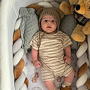 Kian participe au concours pour gagner de l'argent avec cette photo : baby, baby_clothing, bear_ears, braided_bumper, brown_shoes, child, crib, cute, indoor, infant, knit_hat, person, pillow, plush_toy, portrait, resting, sleeping_area, soft_toys, striped_onesie, toddler
