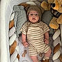 baby, baby_clothing, bear_ears, braided_bumper, brown_shoes, child, crib, cute, indoor, infant, knit_hat, person, pillow, plush_toy, portrait, resting, sleeping_area, soft_toys, striped_onesie, toddler